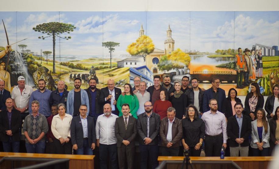 Representantes em pé em frente a um mural